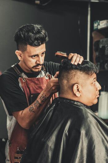 A barber intently focusing on the haircut he's giving his client.